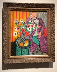 Matisse painting of a woman with a vase of flowers on a table