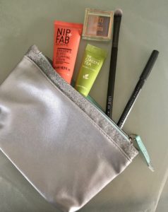 cosmetics spilling out of Ipsy Snow Globe silvery makeup bag, neversaydiebeauty.com