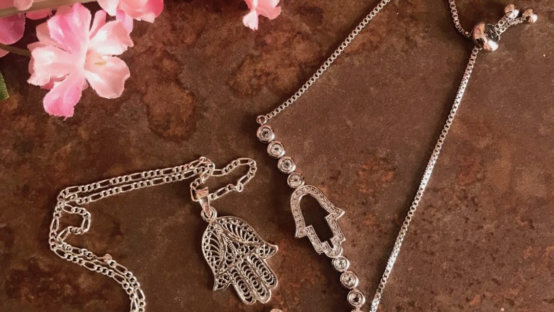 silver necklace and bracelet with the hamsa symbol as centerpiece, neversaydiebeauty.com