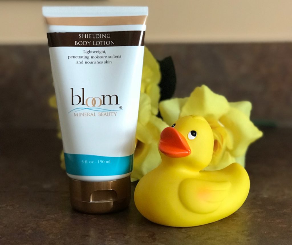 tube of Bloom Minerals Shielding Body Lotion with a yellow rubber duck nearby, neversaydiebeauty.com