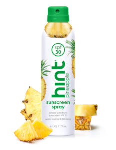 Hint Pineapple Spray Sunscreen bottle surrounded by pineapple slices, neversaydiebeauty.com