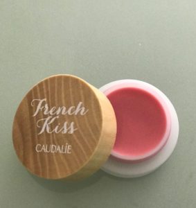 open pot of Caudalie French Kiss Tinted Lip Balm in natural pink shade, Innocence, neversaydiebeauty.com