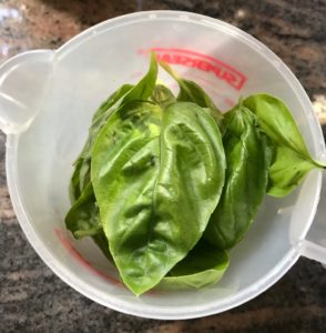 basil leaves in a measuring cup