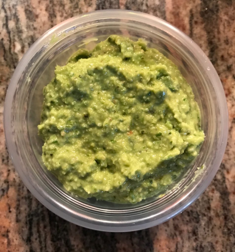 finished garlic scape pesto in plastic container, neversaydiebeauty.com