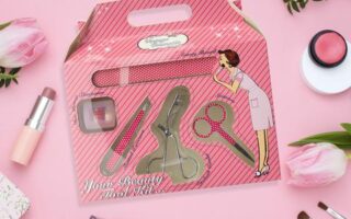 pink beauty tool set in its pink box against a pink background with other makeup items