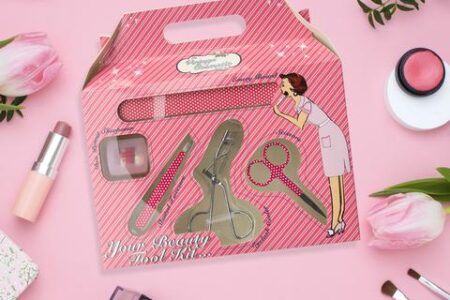 pink beauty tool set in its pink box against a pink background with other makeup items