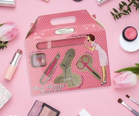 pink beauty tool set in its pink box against a pink background with other makeup items