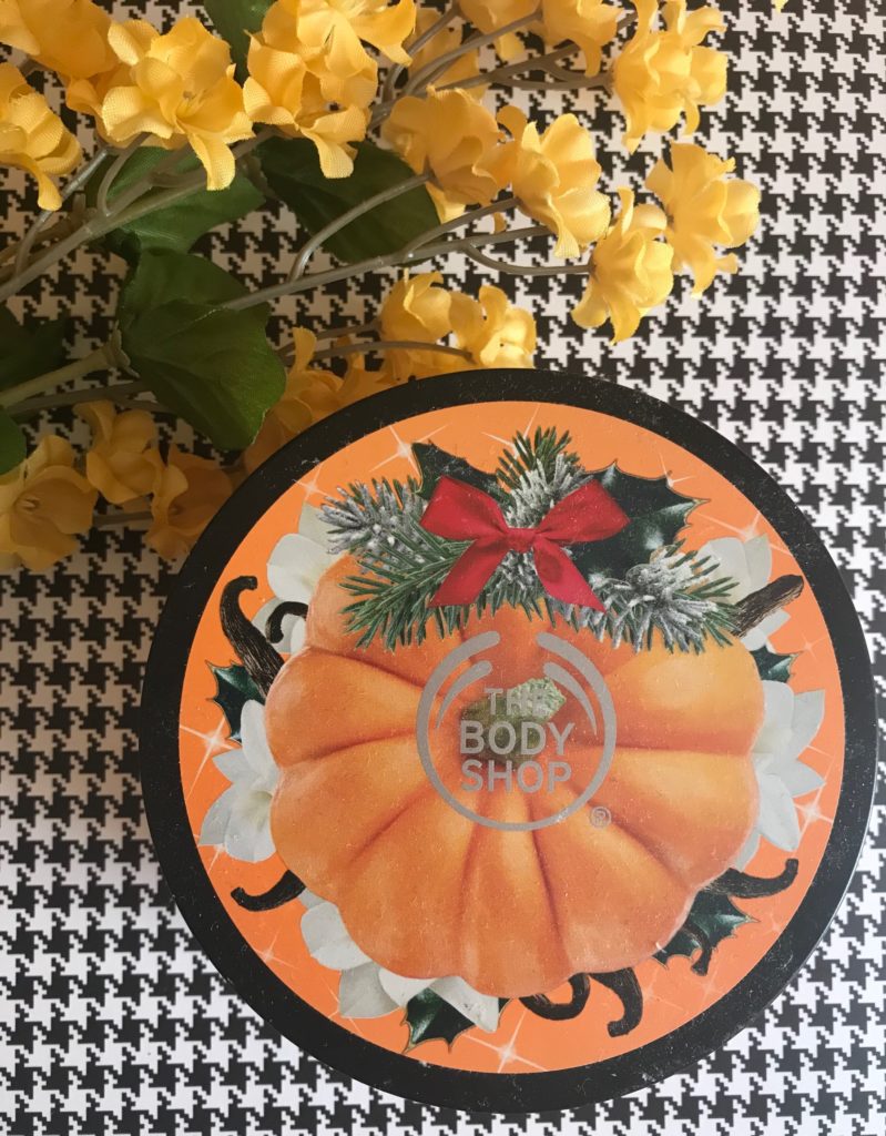 top of the 2017 tub of The Body Shop Vanilla Pumpkin Body Butter decorated with a pumpkin, vanilla bean pods and flowers, neversaydiebeauty.com