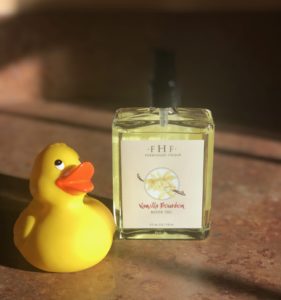 clear glass pump bottle of gold Farmhouse Fresh Vanilla Bourbon Body Oil with a yellow rubber duck nearby, neversaydiebeauty.com