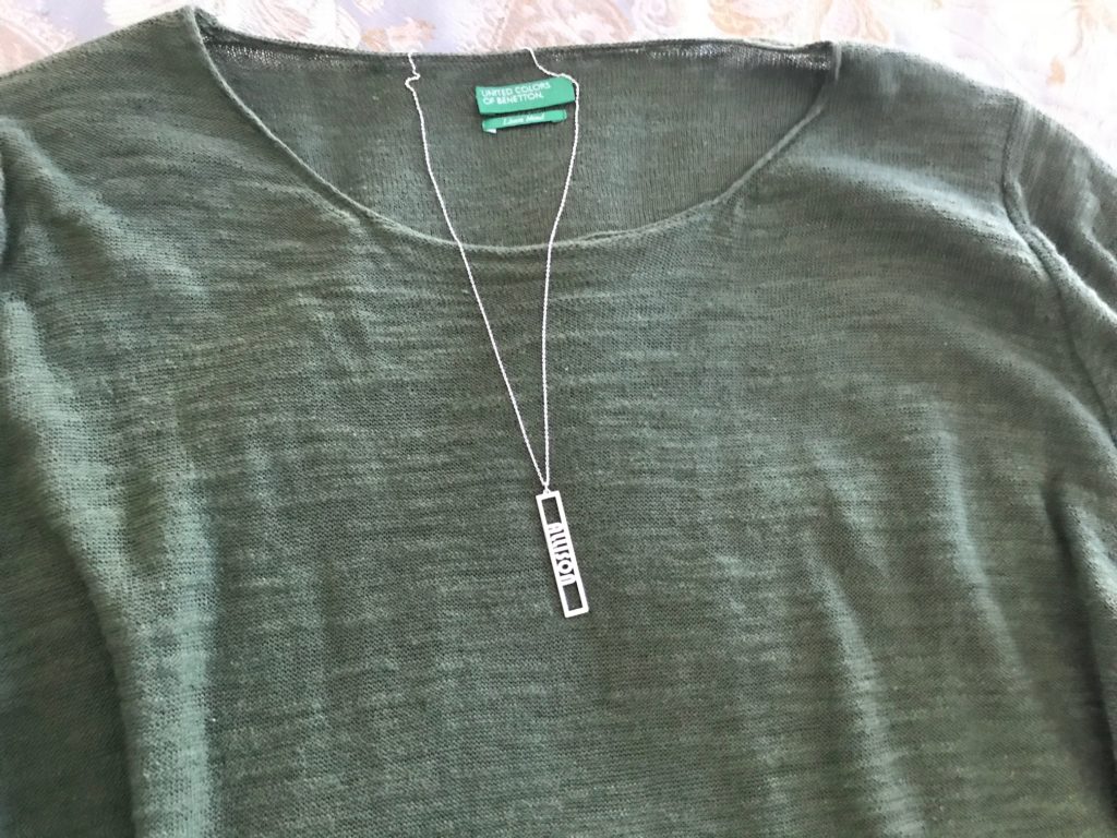my sterling silver name necklace from Messages In Metal against a green top