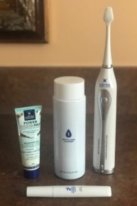 the four items in the Luster Power White Pro Sonic Dental Whitening kit: electric toothbrush, accelerant rinse, stain lifting serum and toothpaste, neversaydiebeauty.com