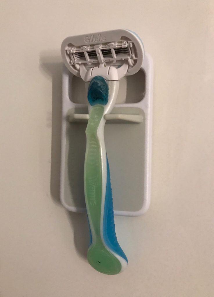 my razor hanging on the Bladetap unclogging device on my shower stall, neversaydiebeauty.com