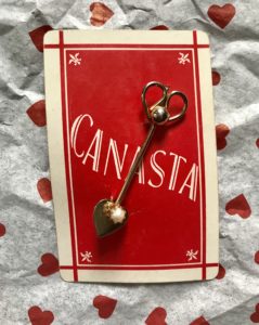 gold pin with heart-shaped spade on a Canasta card, neversaydiebeauty.com