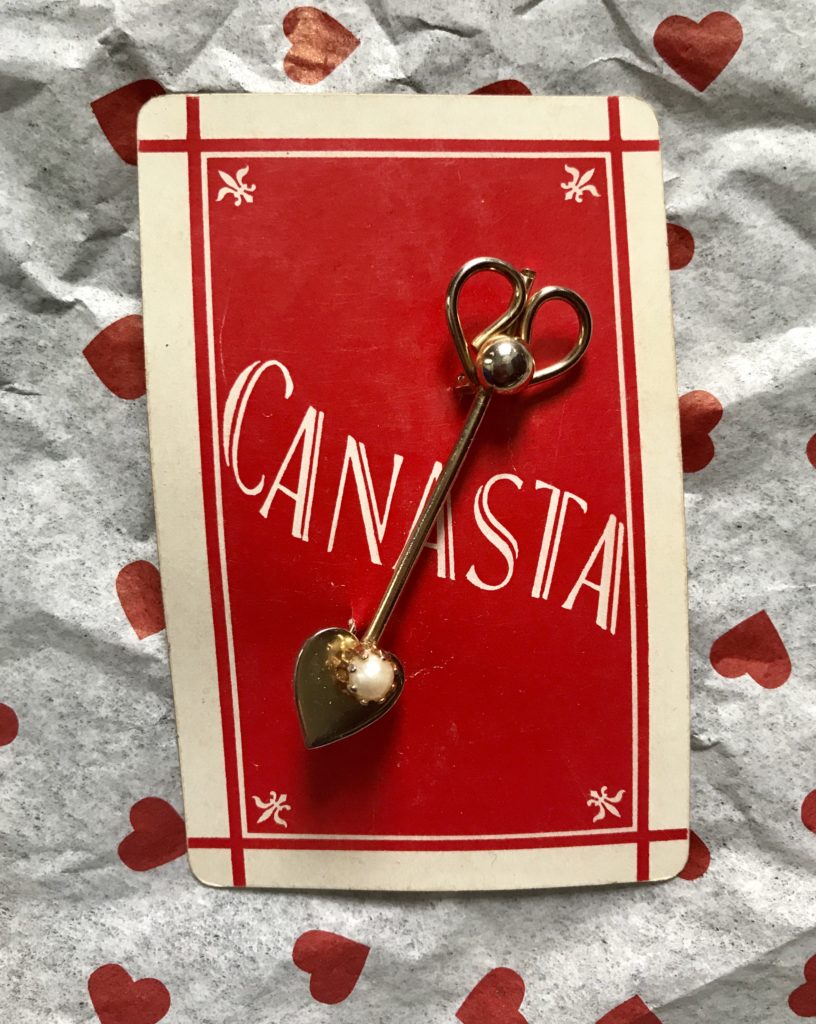 gold pin with heart-shaped spade on a Canasta card, neversaydiebeauty.com