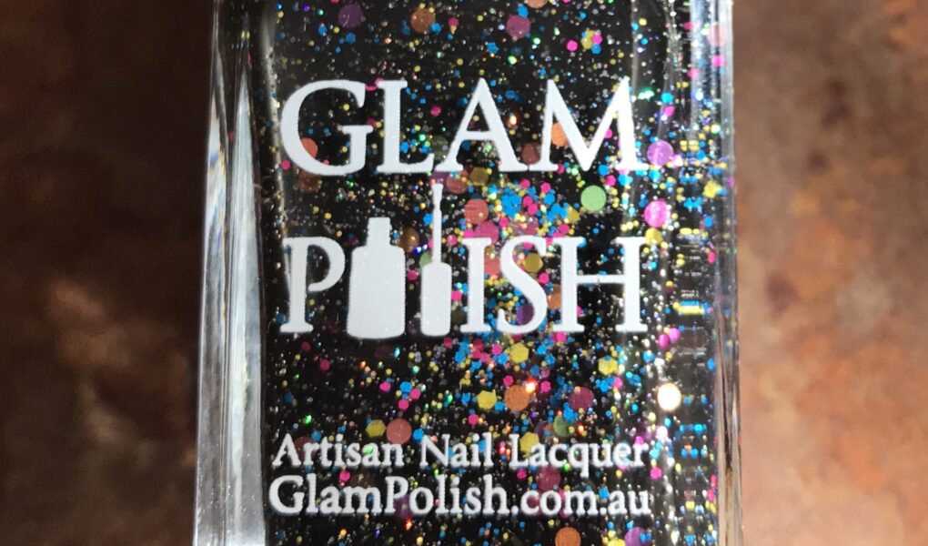 closeup of the bottle of Glam Polish "We Will Rock You 2.0", a black polish with glitter and flakes, neversaydiebeauty.com