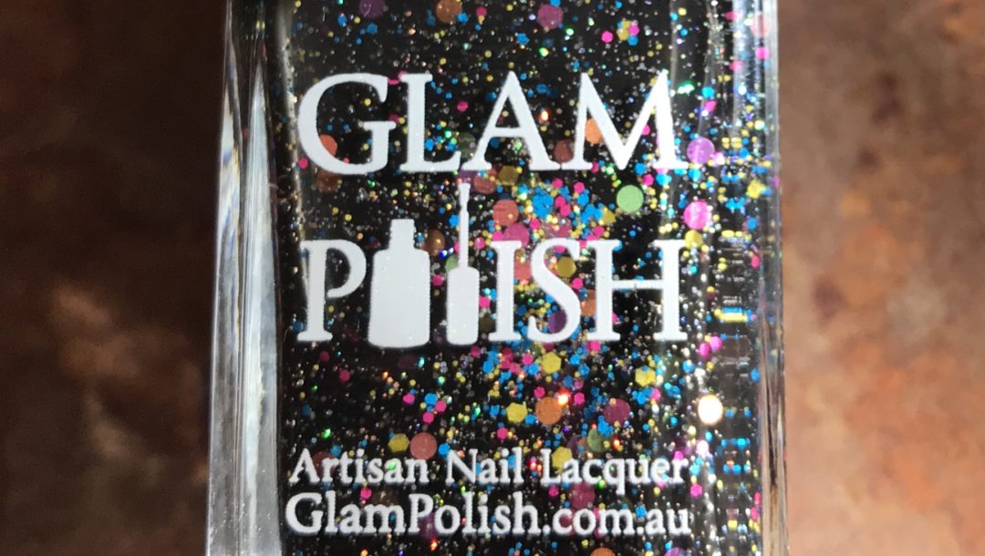 closeup of the bottle of Glam Polish "We Will Rock You 2.0", a black polish with glitter and flakes, neversaydiebeauty.com