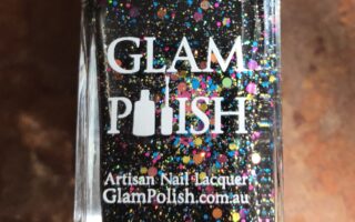 closeup of the bottle of Glam Polish "We Will Rock You 2.0", a black polish with glitter and flakes, neversaydiebeauty.com