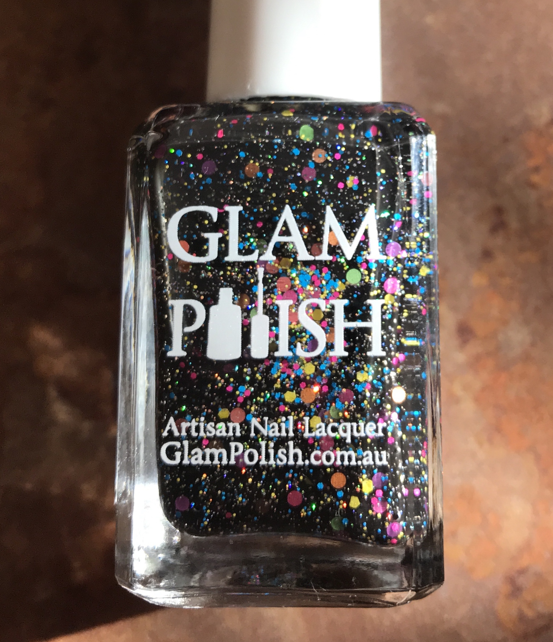 closeup of the bottle of Glam Polish "We Will Rock You 2.0", a black polish with glitter and flakes, neversaydiebeauty.com