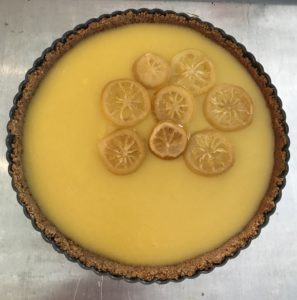 lemon tart in the tart pan with candied lemon slices on top, neversaydiebeauty.com