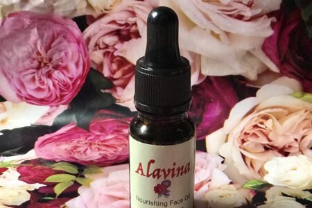 bottle of organic Alavina Nourishing Face Oil against a floral background, neversaydiebeauty.com