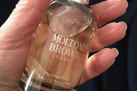 me holding the spray bottle of Molton Brown Muddled Plum eau de toilette, neversaydiebeauty.com