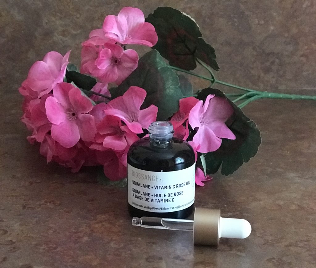 green glass dropper bottle of Biossance Squalane Vitamin C Rose Oil, open to show the clear oil in the dropper