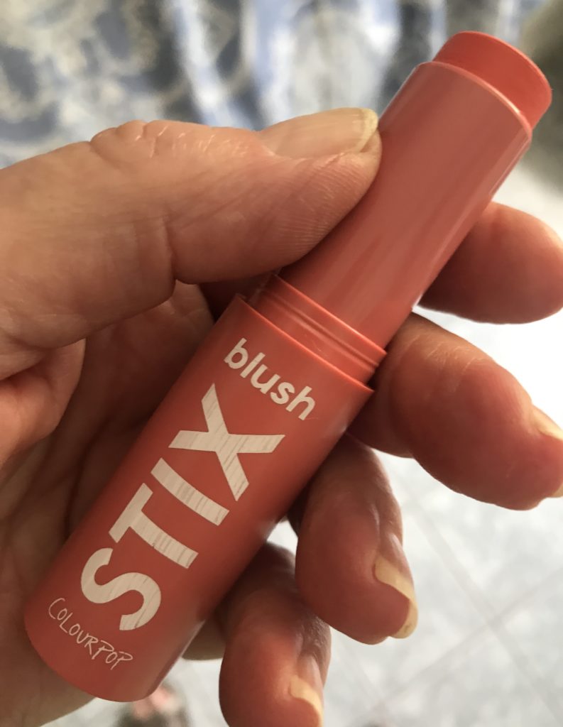 holding an open tube of ColourPop Blush Stix to show the size