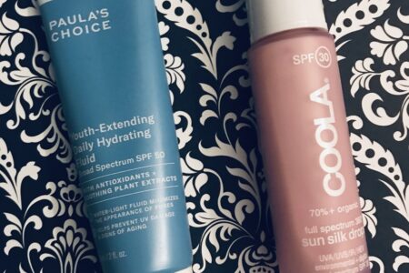 tube of Paula's Choice Youth Extending Hydrating Fluid SPF 50 and bottle of Coola Sun Silk Drops SPF 30