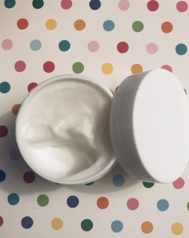 open travel size jar of Derma E Hydrating Night Cream showing the rich, white cream