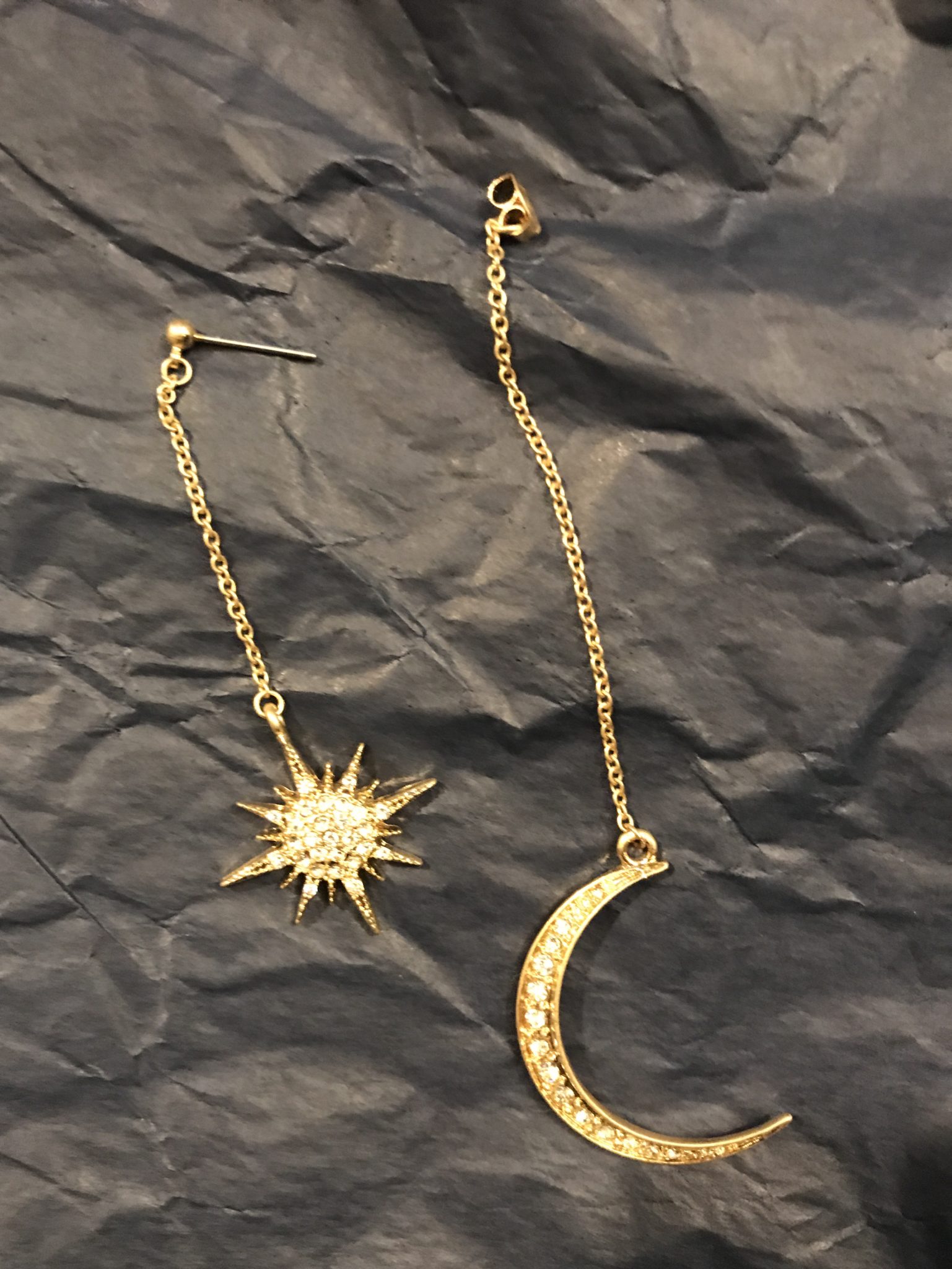 the two parts of the Lahaina star and moon earring, each dangling on a golden chain