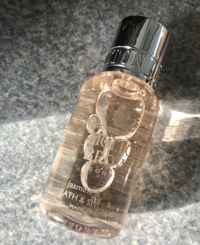 closeup of mini bottle of Molton Brown Jasmine & Sun Rose Shower Gel one ounce bottle