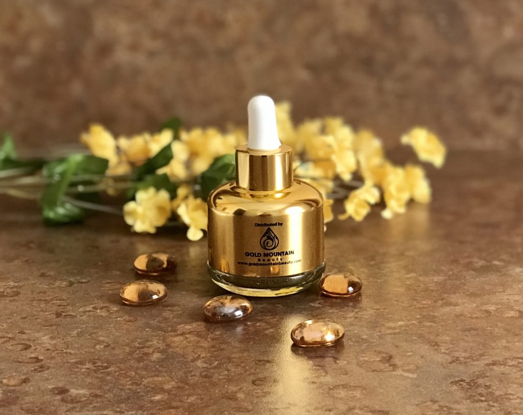 bottle of Gold Mountain Beauty Organic Rosehip Oil and Gold Dust Elixir in a gold dropper bottle