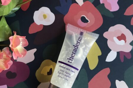 tube of Theraderm Anti-Aging Lip Complex against a flowered background