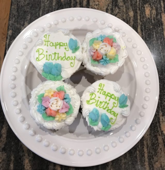 4 flowered birthday cupcakes on a white plate