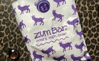 white paper bag that is decorated with fanciful pictures of purple goats on the Zum Bar soap white bag