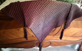 shades of purple Dragon Belly shawl draped over the footboard of my bed