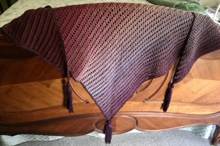 shades of purple Dragon Belly shawl draped over the footboard of my bed